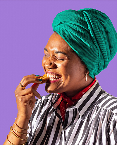 photo of a woman tasting a piece of chicken
